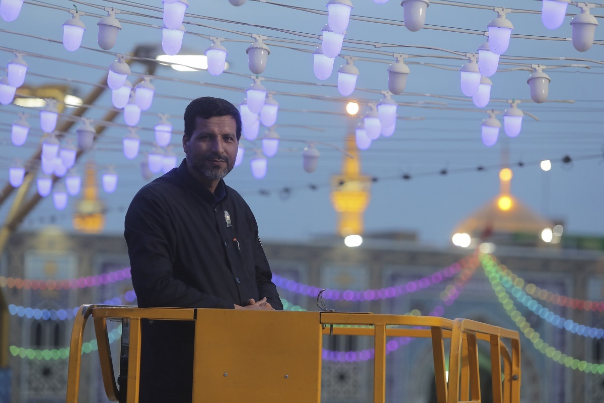 خادم حرم امام‌رضا (ع) سال‌هاست در ارتفاع ۲۴ متری چراغانی و نصب کتیبه‌های مناسبتی را اجرا می‌کند
